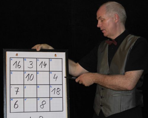 Zauberer Thies führt seinen Zaubertrick 'Das magische Quadrat' an einem Whiteboard vor